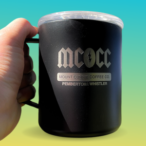 Black insulated camp mug with MCCC logo and laser-etched Mount Currie Coffee Co. Pemberton Whistler branding held against watercolor background